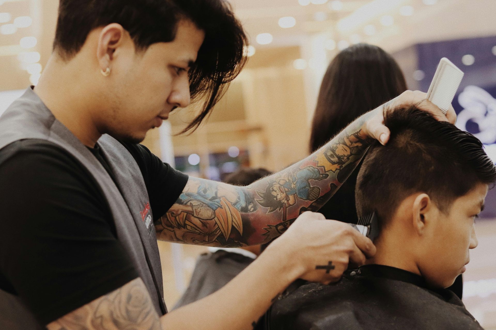 Barber using clippers to cut a client's hair in a barbershop.