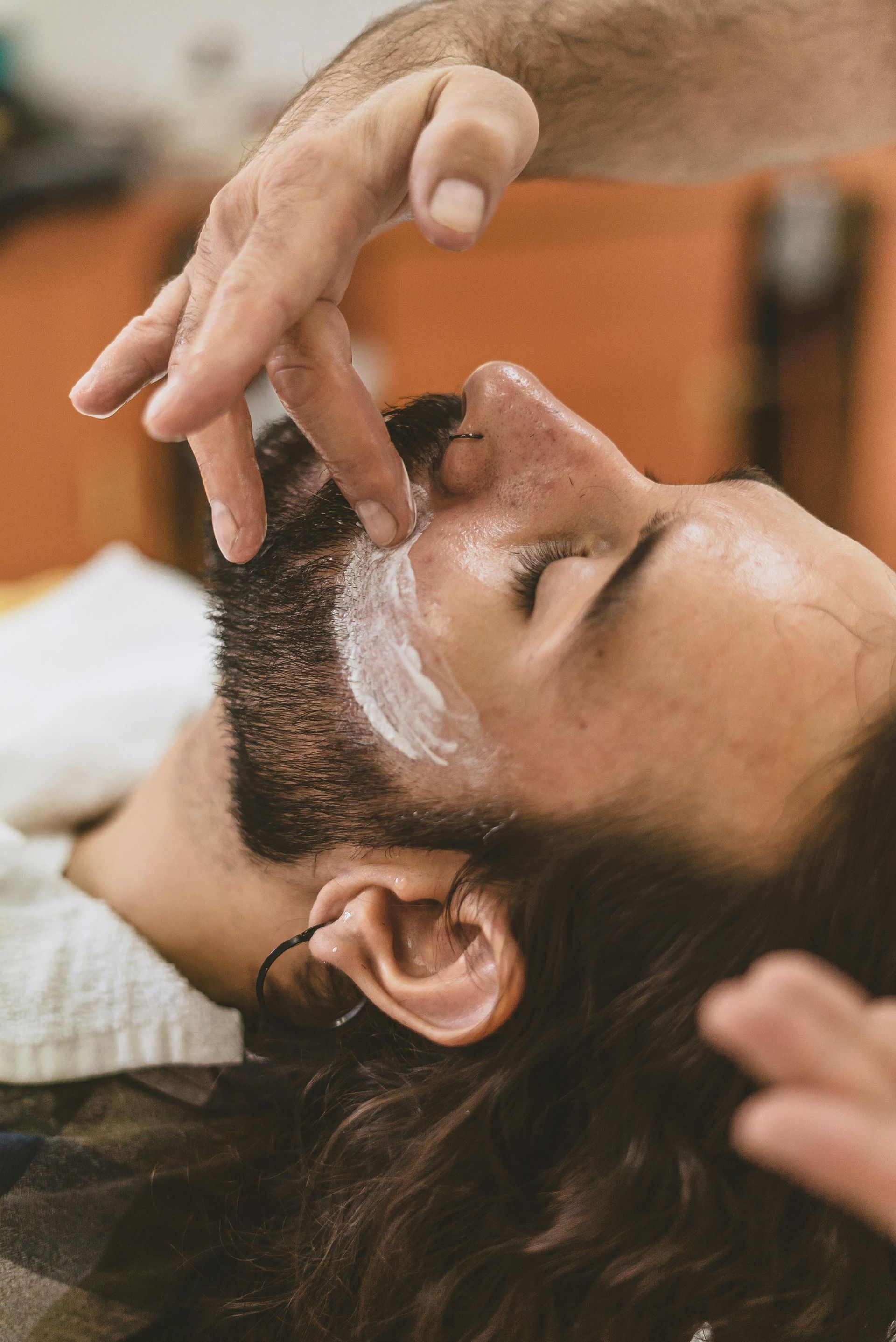 A person receiving a facial treatment; cream is applied to the face and beard.