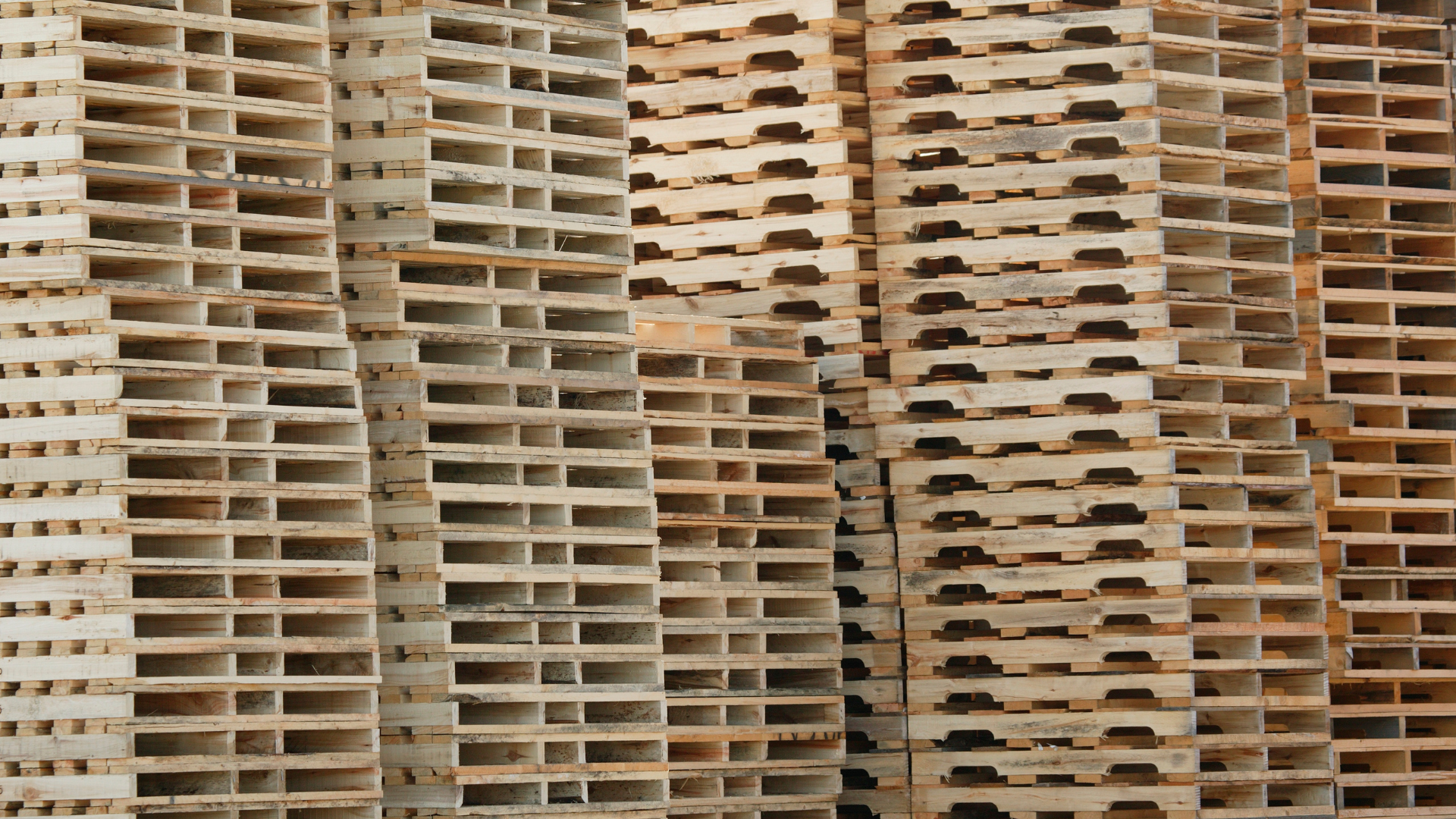 A man is lifting a cardboard box on a wooden pallet.