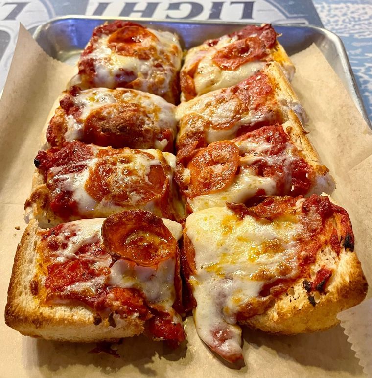 Tray of square pizza slices with melted cheese and tomato sauce on parchment paper