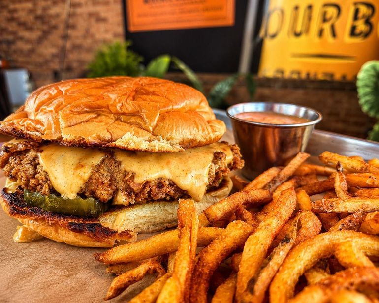 Juicy burger with fries and dipping sauce on a wooden table