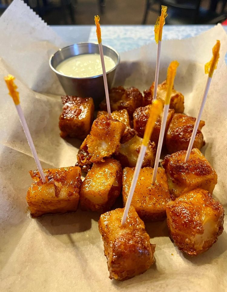 Skewered golden fried bites with dipping sauce on parchment paper