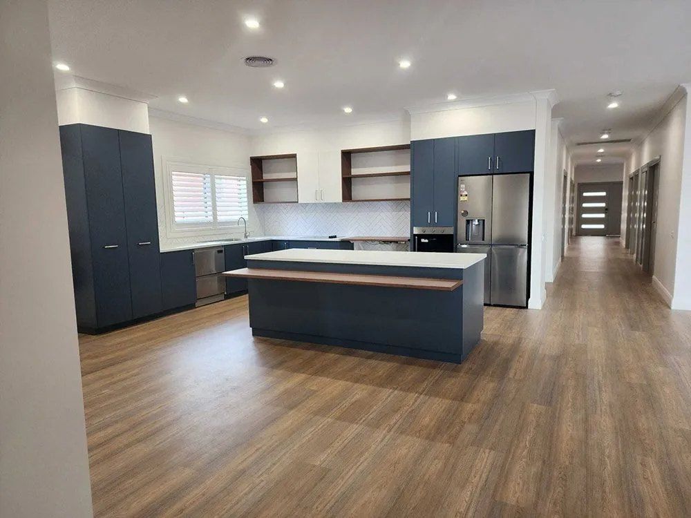 A Kitchen With Blue Cabinets and a Large Island in the Middle of the Room — Chandolin Construction in Bathurst, NSW
