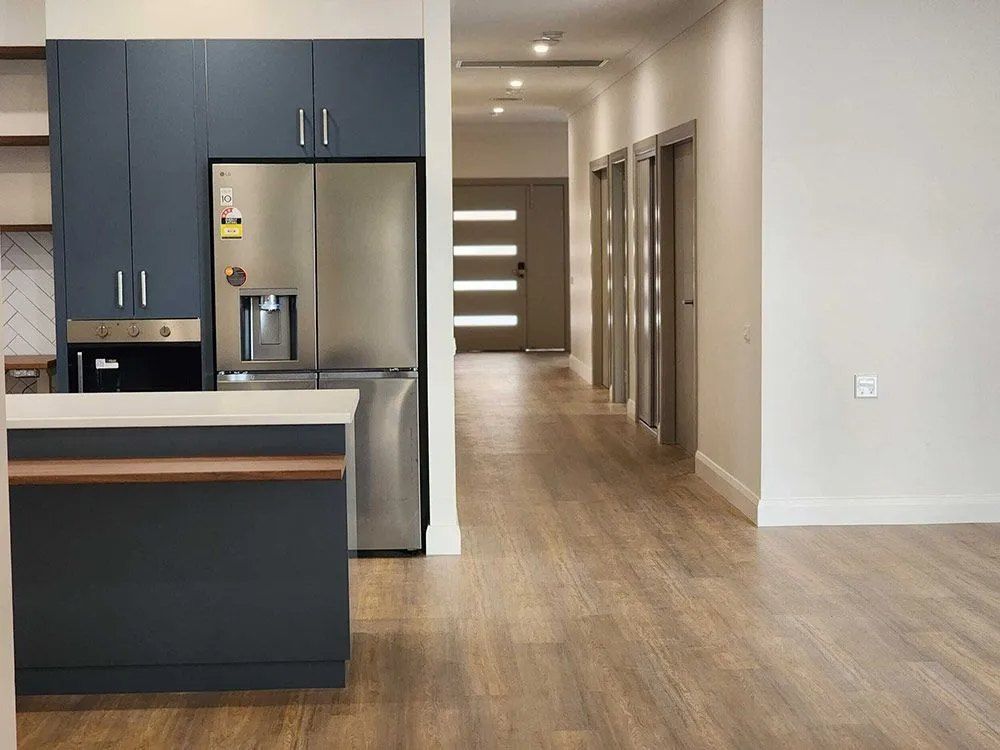 A Kitchen With a Stainless Steel Refrigerator and a Wooden Floor — Chandolin Construction in Bathurst, NSW
