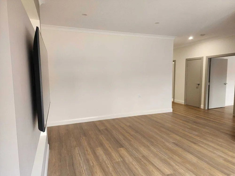 An Empty Living Room With Hardwood Floors and White Walls — Chandolin Construction in Bathurst, NSW