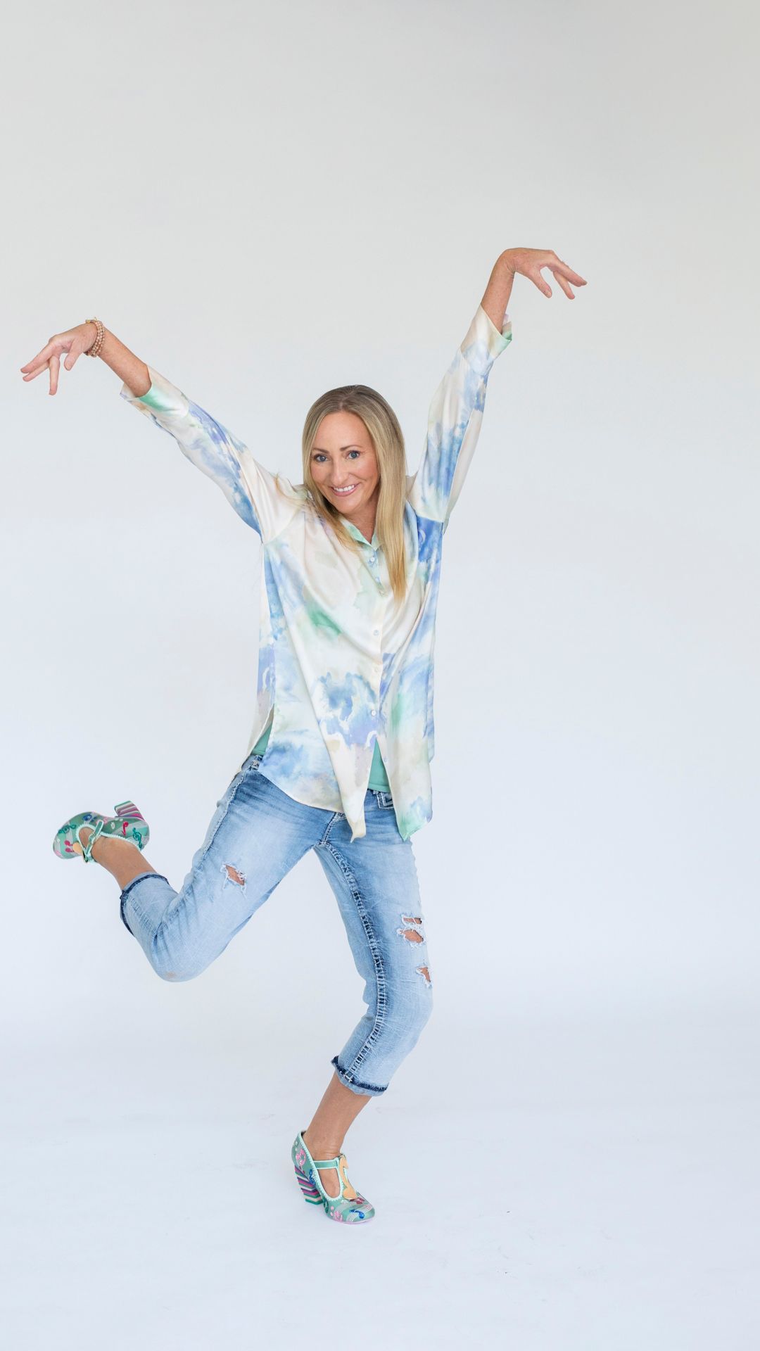 Woman posing playfully in a colorful outfit against a plain white background