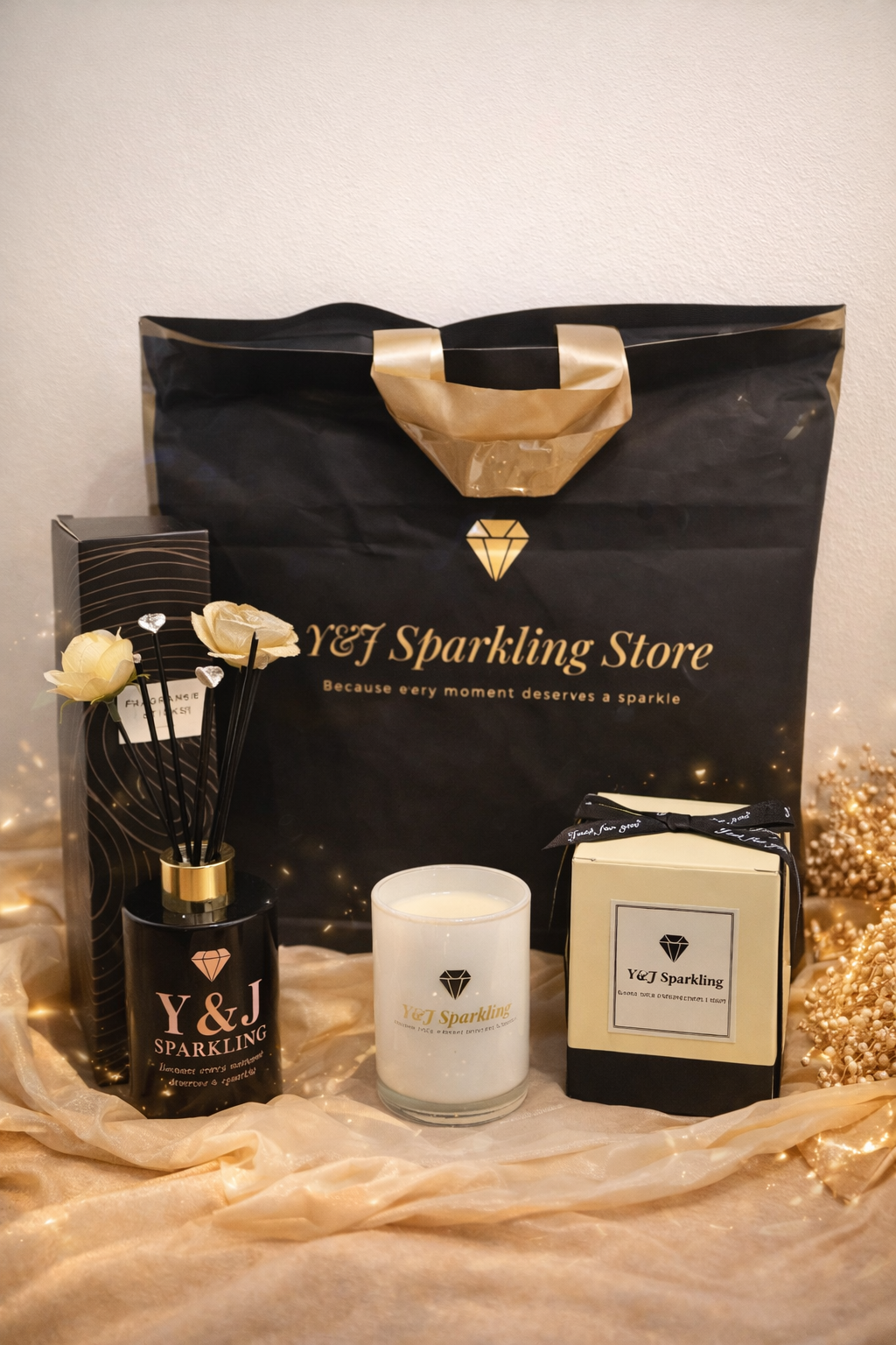 Cadeauset: zwarte boodschappentas, kaars, geurdiffuser en een ingepakte doos op een gouden doek met fonkelende lichtjes.