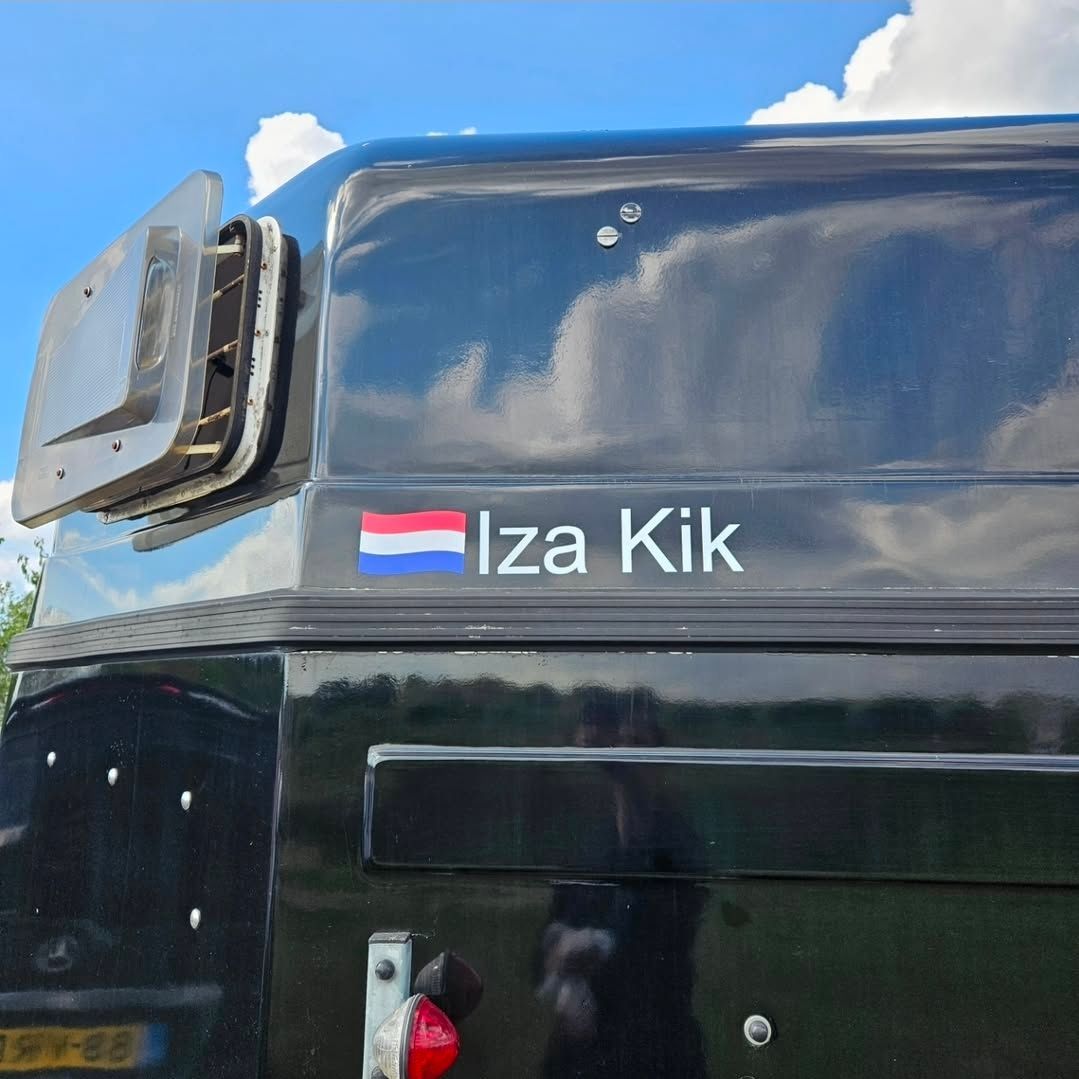 Een zwart voertuigoppervlak met de Nederlandse vlag en de witte tekst 