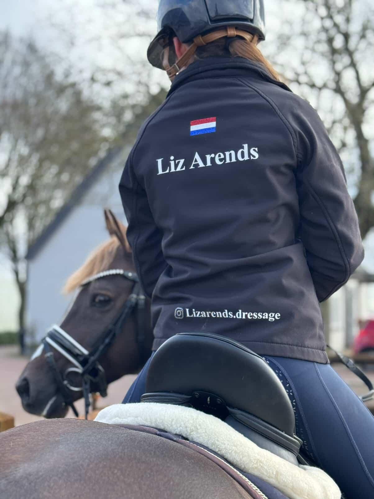 Een persoon draagt ​​een jas met een Nederlandse vlag en 