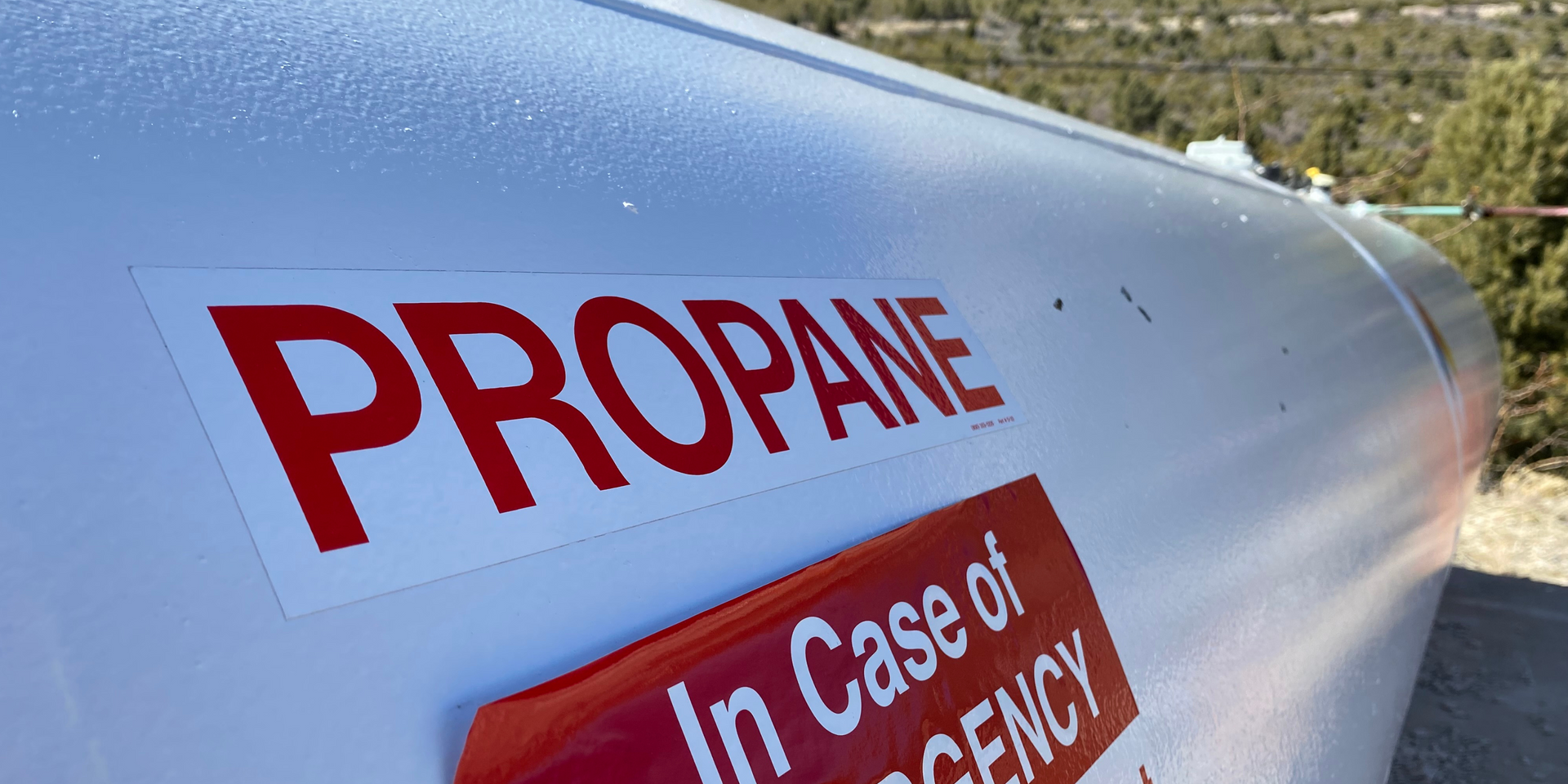 A close up of a propane tank with a red sign on it.