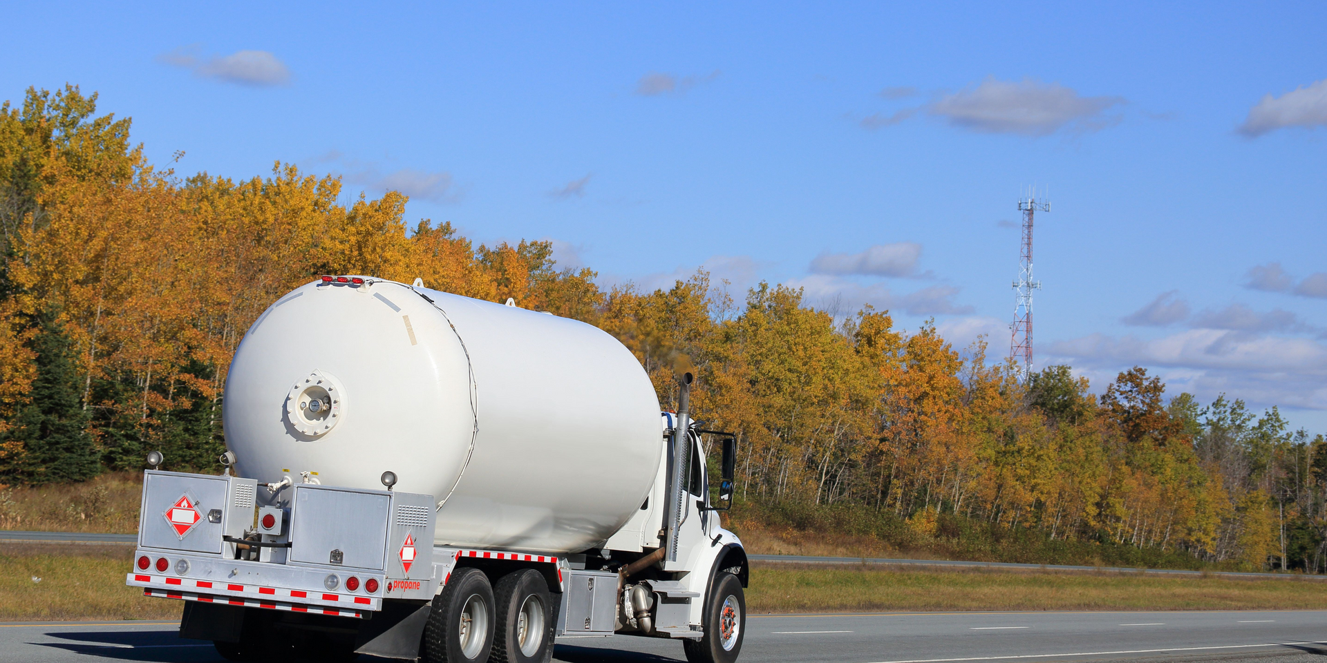 A white tanker truck is driving down a highway.