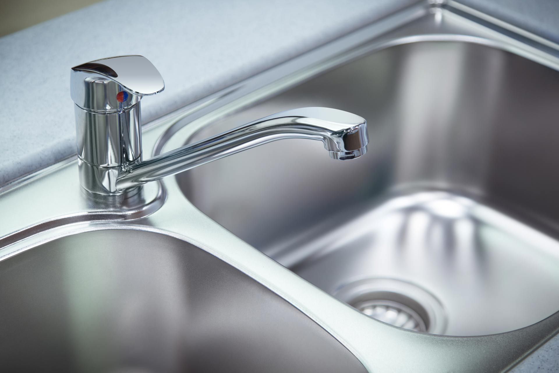 A close up of a stainless steel kitchen sink with a faucet