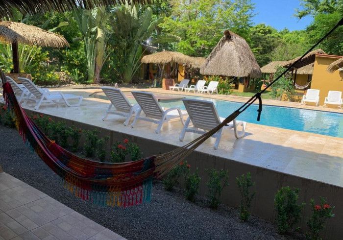 A hammock is sitting next to a swimming pool. Hamacas hotel 