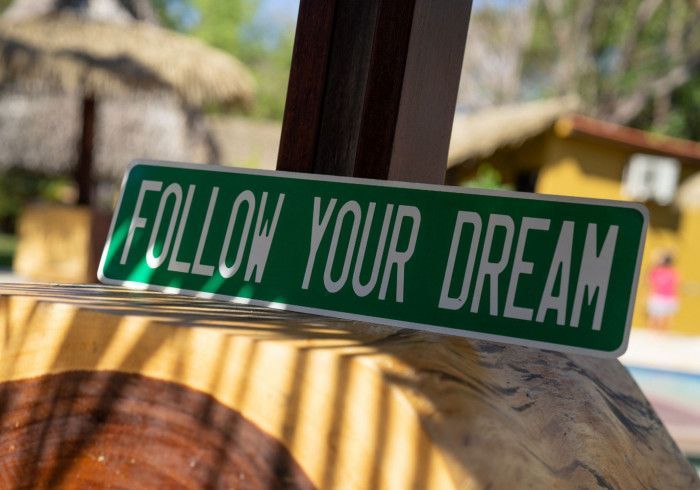 A green sign that says follow your dream on it. Hamacas hotel 