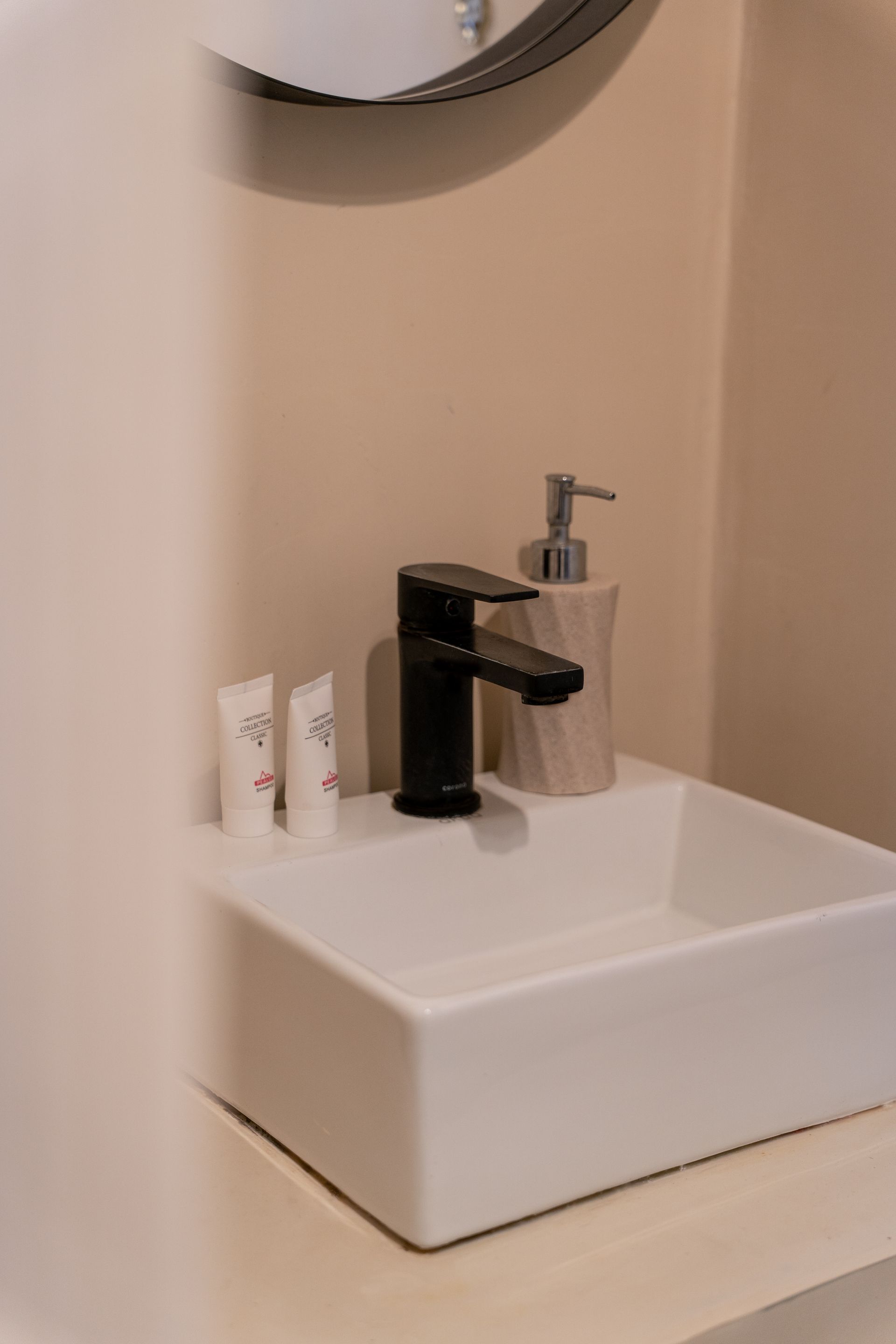 Modern bathroom sink with black faucet, soap dispenser, and toiletries on a counter