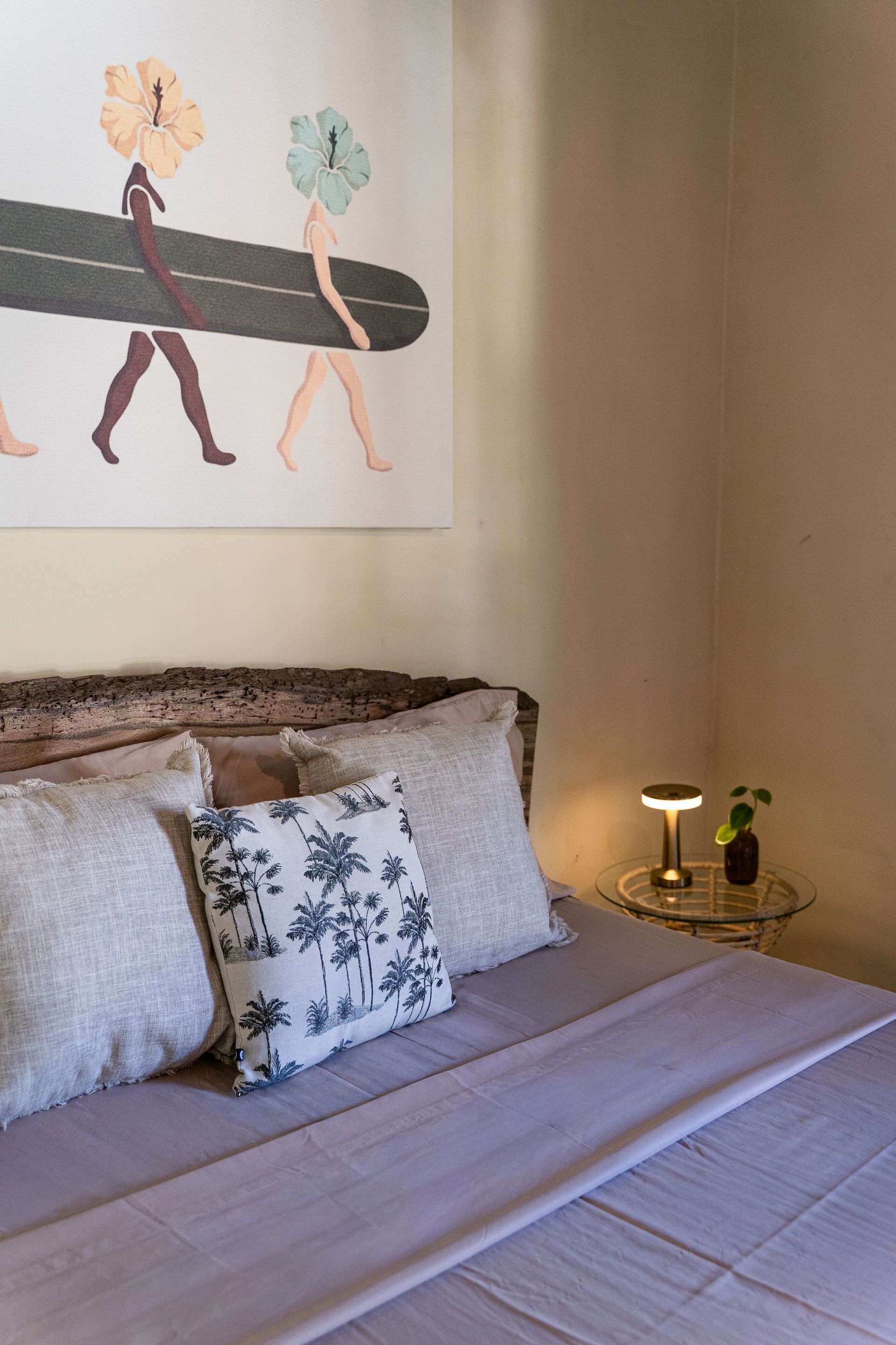 Cozy bedroom with bed, floral pillows, bedside lamp, and abstract wall art above the headboard