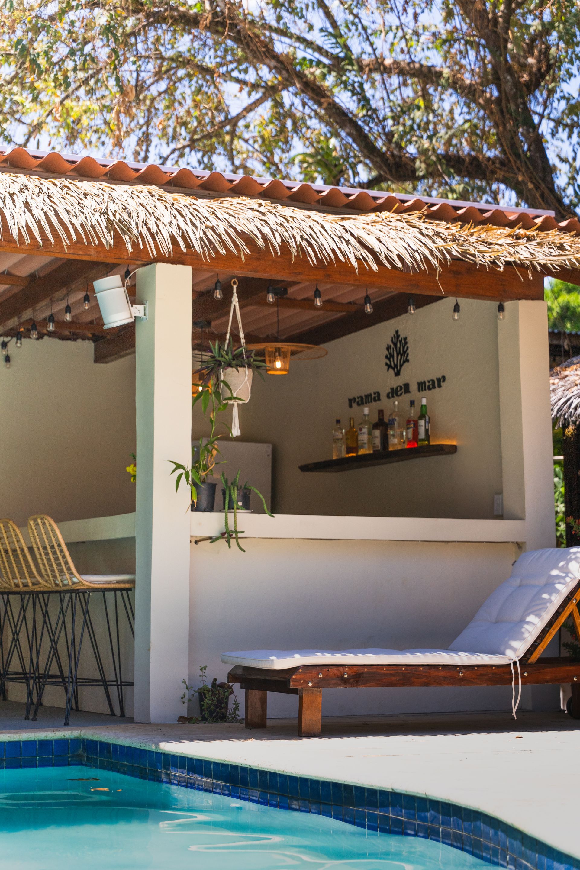 Poolside cabana with thatched roof, white walls, and lounge chair by the water