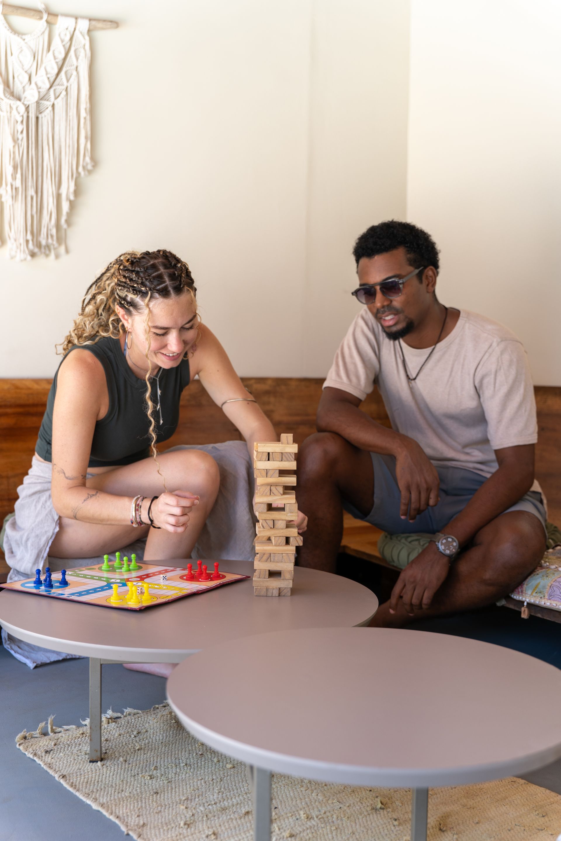 Two people playing Jenga beside round coffee tables in a cozy living room