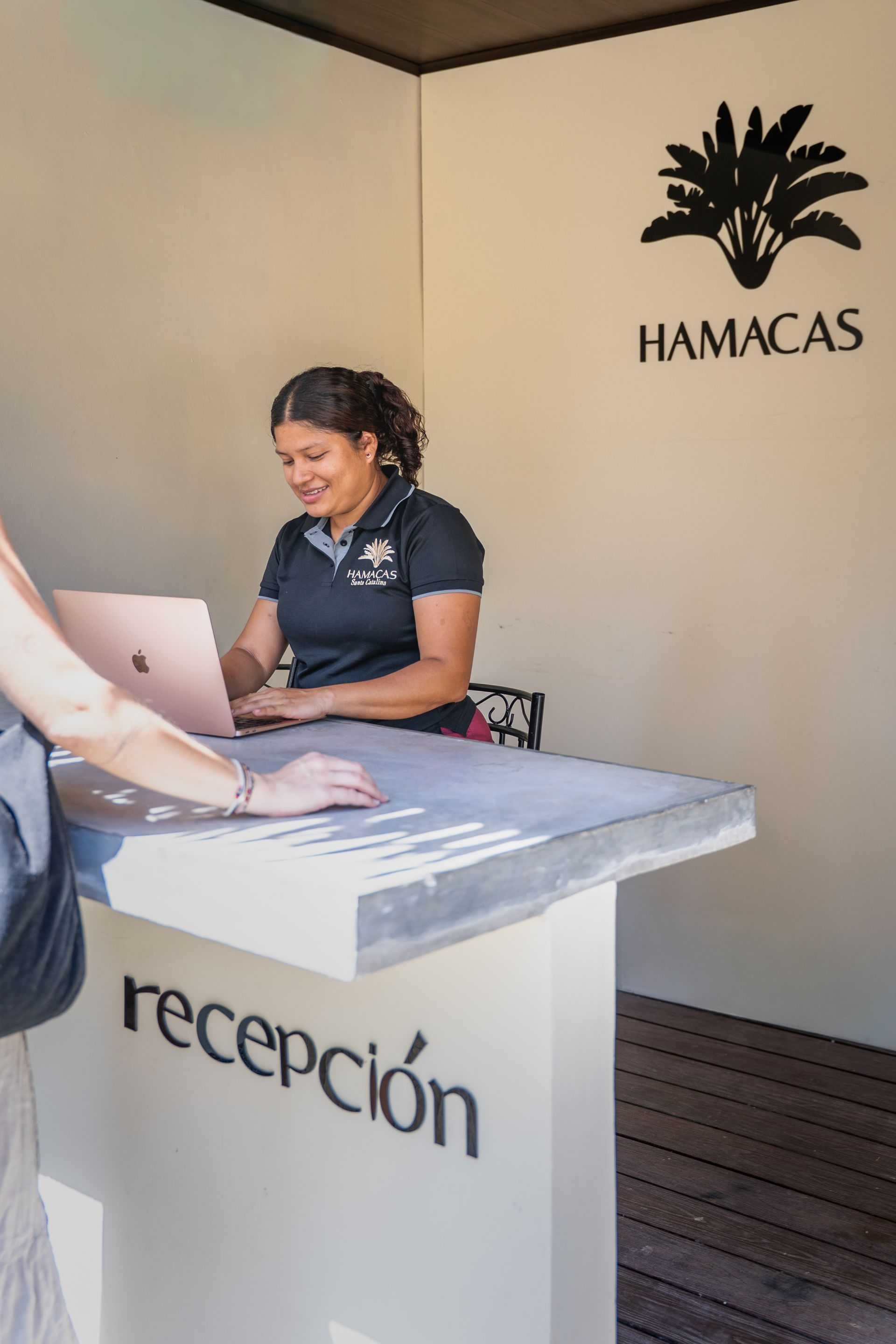 Reception desk with a staff member working on a laptop at the Hamacas office kiosk