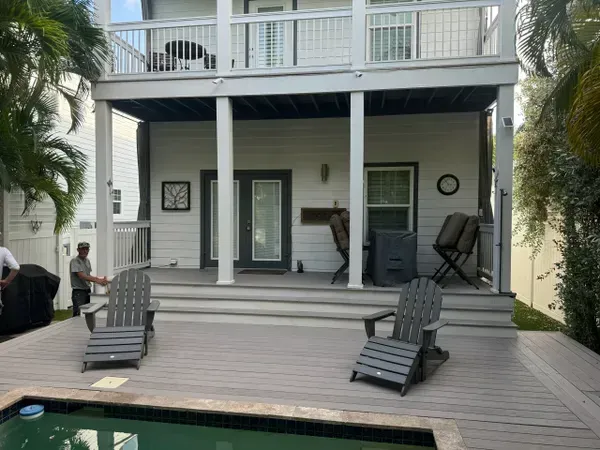 Backyard deck with chairs and a house porch, overlooking a small pool