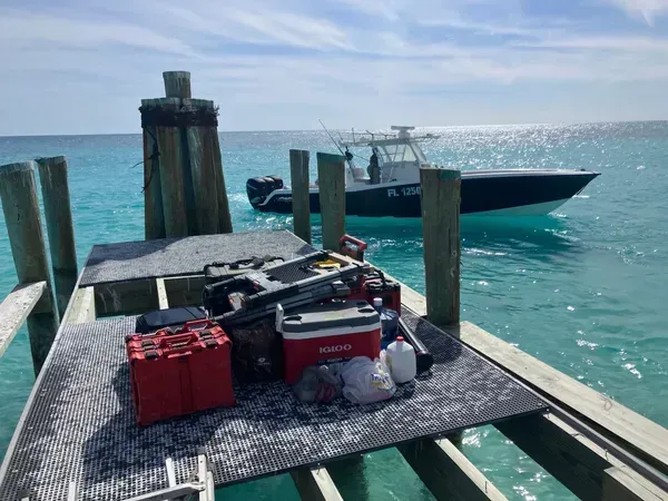 Fishing gear on a dock beside a small boat in bright turquoise water