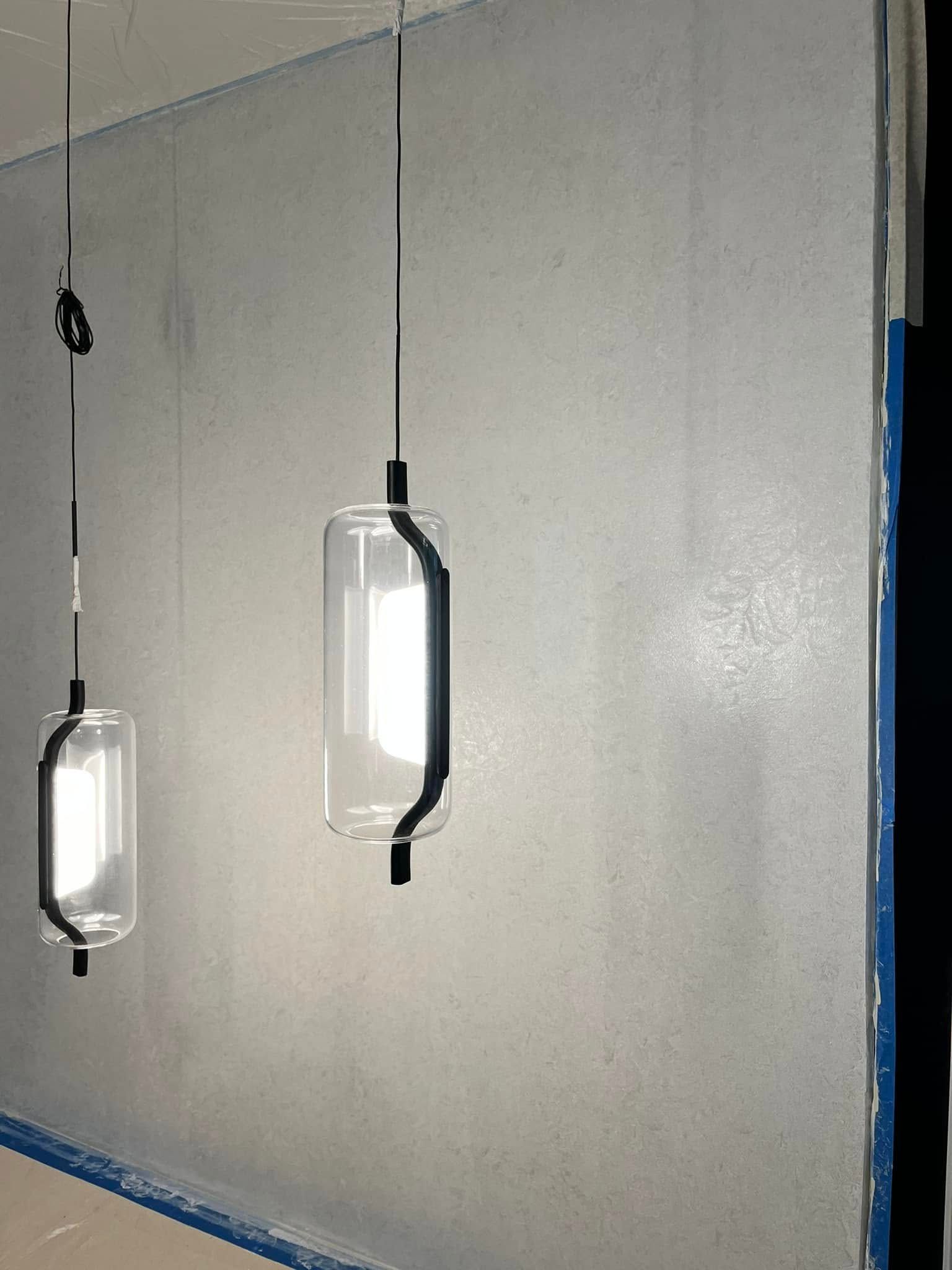 Two hanging work lights casting bright reflections on a blank painted wall