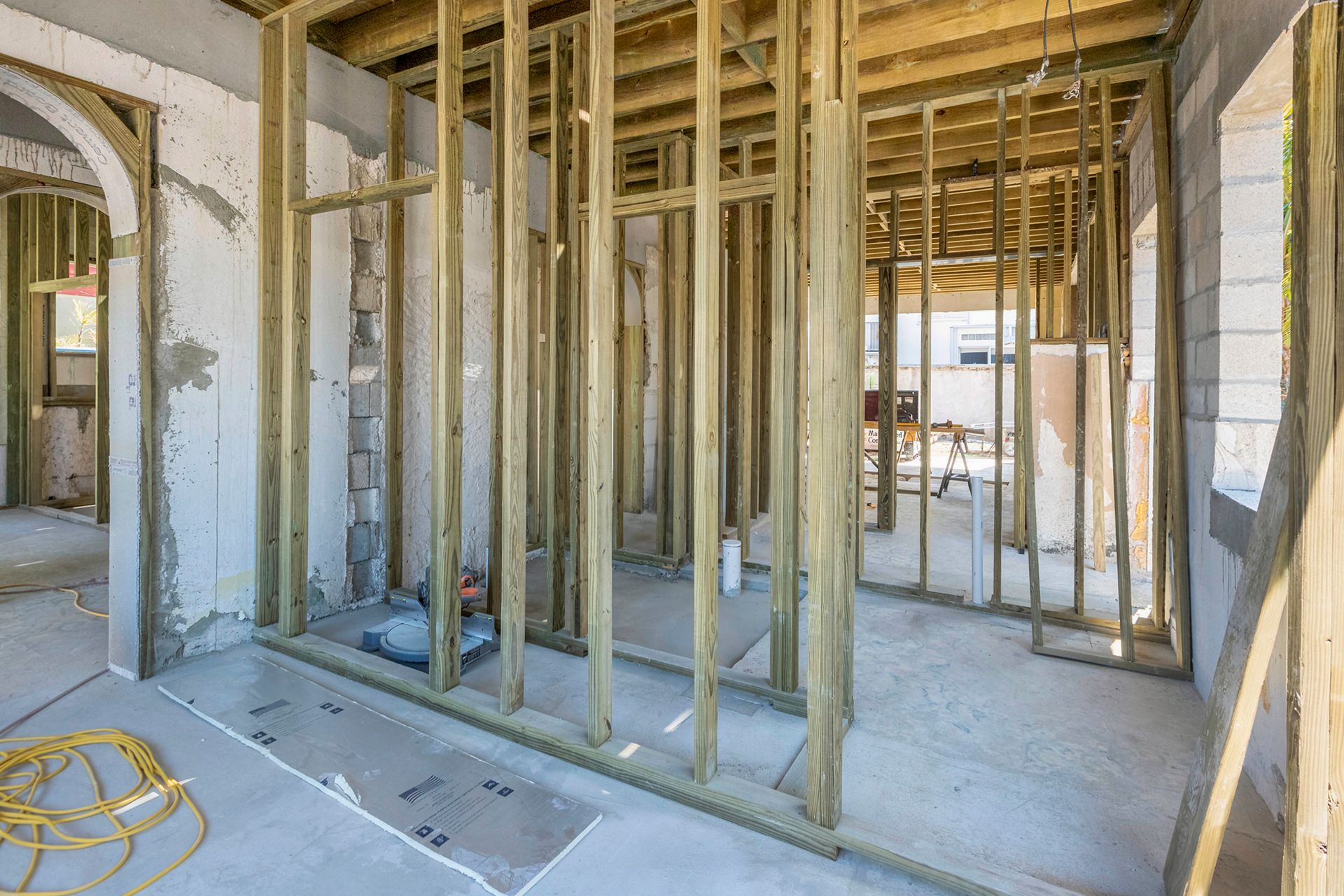 Wooden framework of a building under construction, with open walls and roof, outdoors.