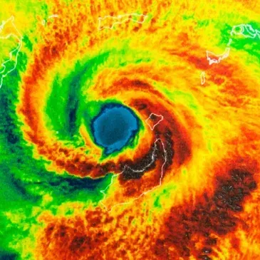 Satellite image of a spiraling hurricane with a dark blue eye over bright orange and green clouds