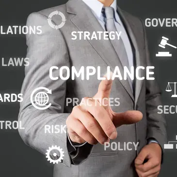 Businessperson in gray suit pointing at “COMPLIANCE” with legal and strategy words in the background