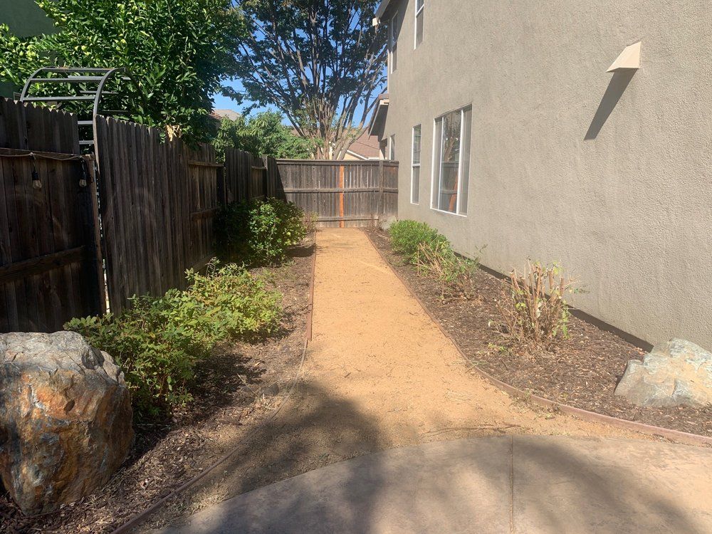 A dirt path leading to a house with a wooden fence.
