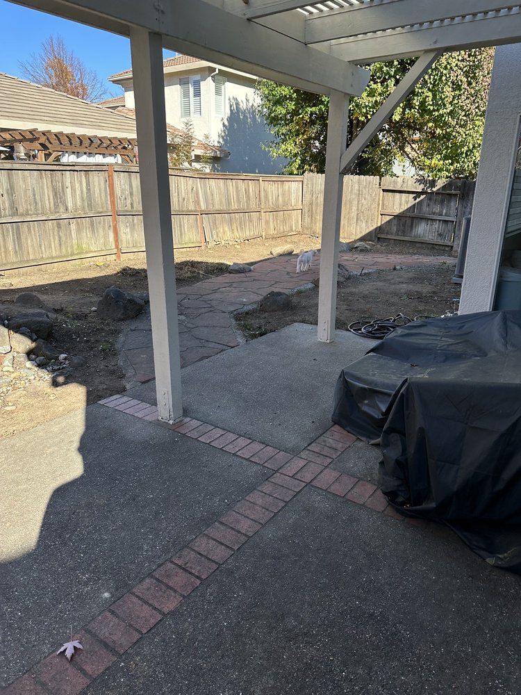 A patio with a grill and a fence in the background.