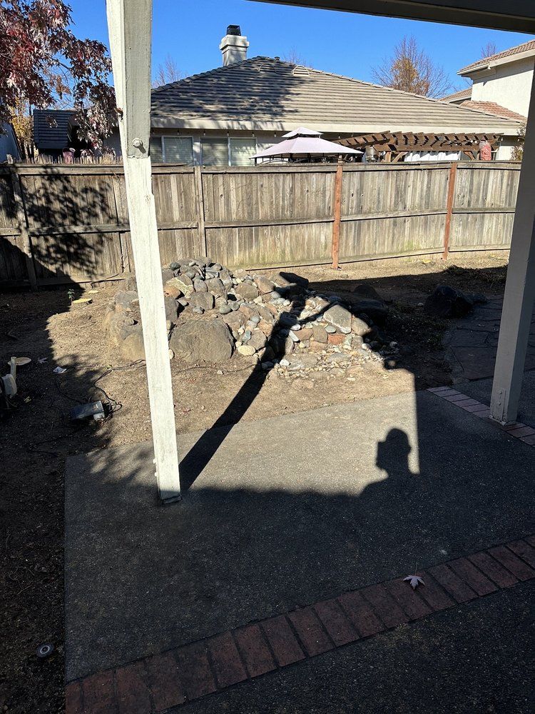 A shadow of a person is cast on the ground in a backyard.