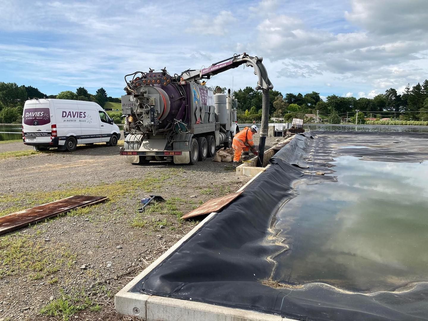 A vacuum truck is pumping water into a pond.