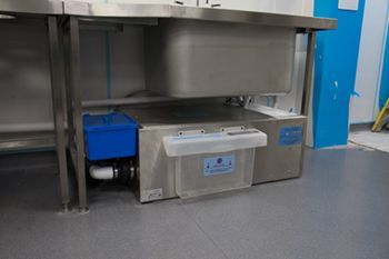 A stainless steel sink is under a stainless steel counter in a kitchen.