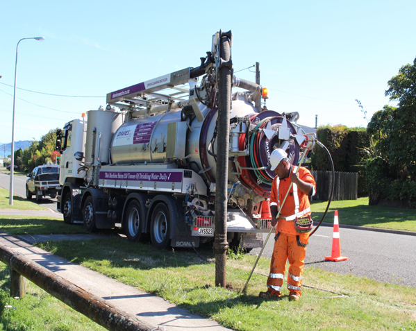 A man is standing in front of a vacuum truck.