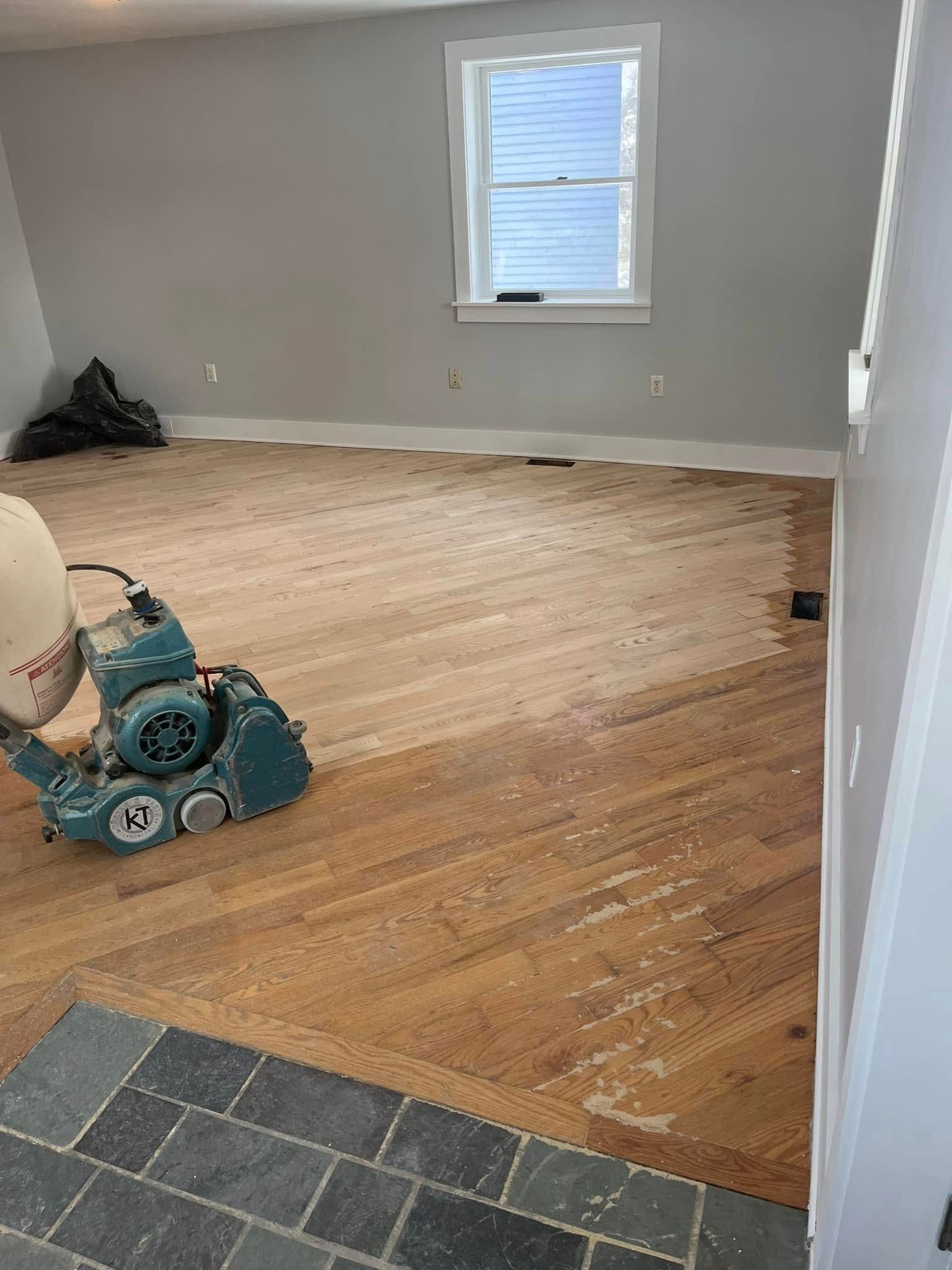 A machine is sanding a wooden floor in a room.