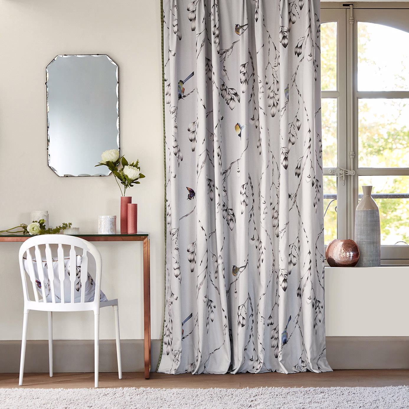 Long draping silver curtains in a bedroom