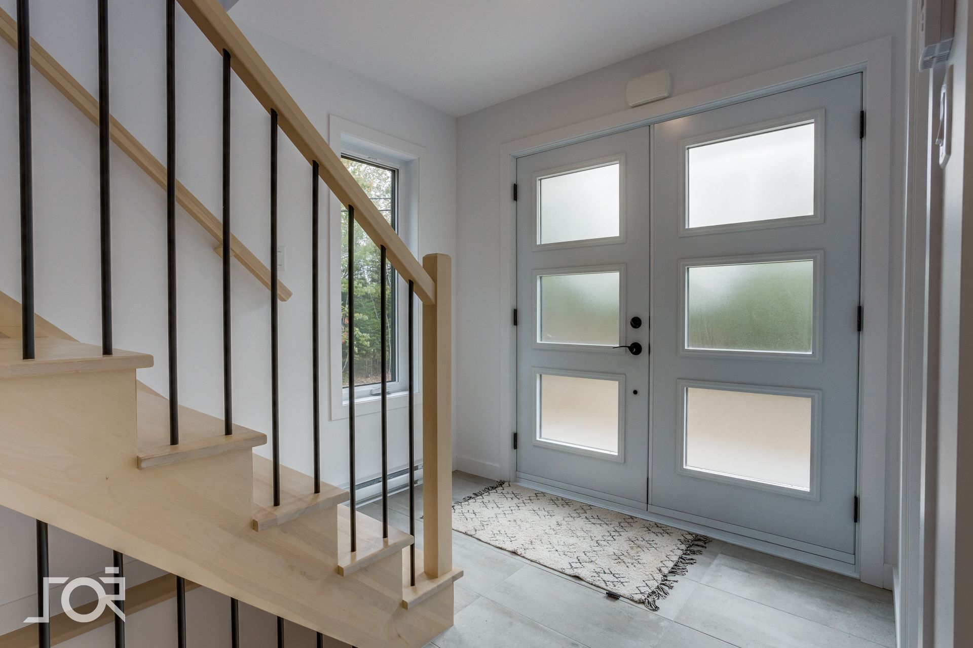 Un couloir avec des escaliers menant à une porte blanche