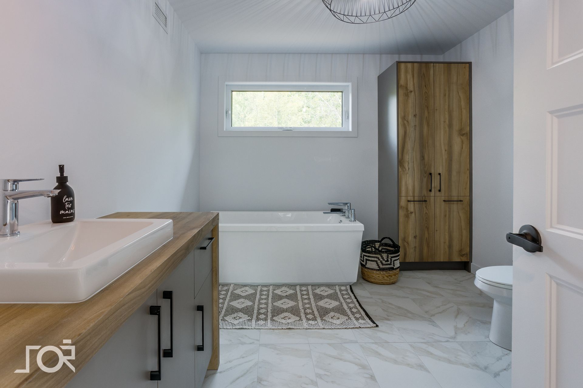 Une salle de bain avec baignoire, lavabo, toilettes et armoires.