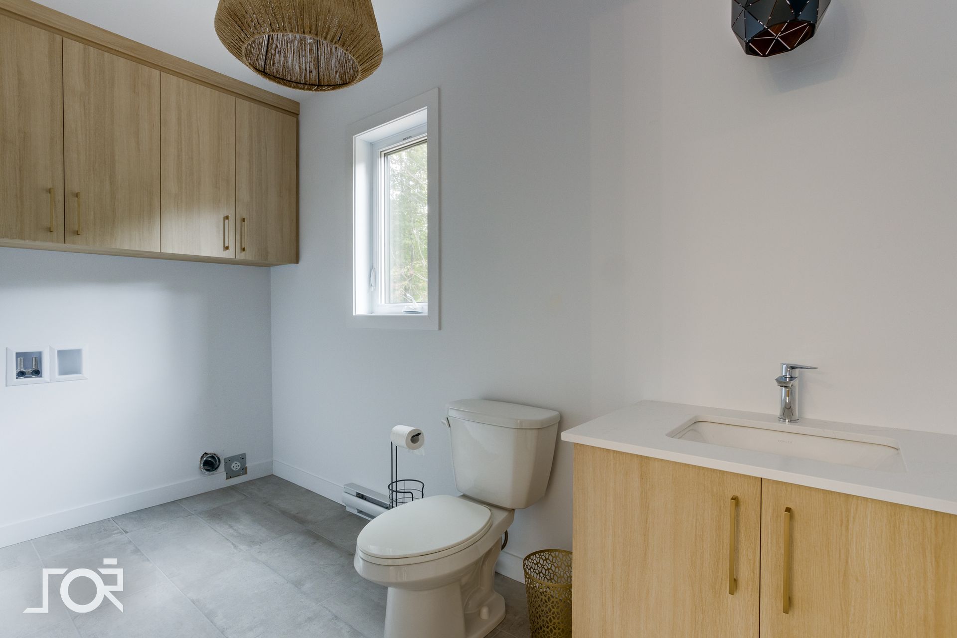 Une salle de bain avec WC, lavabo, placards et fenêtre.