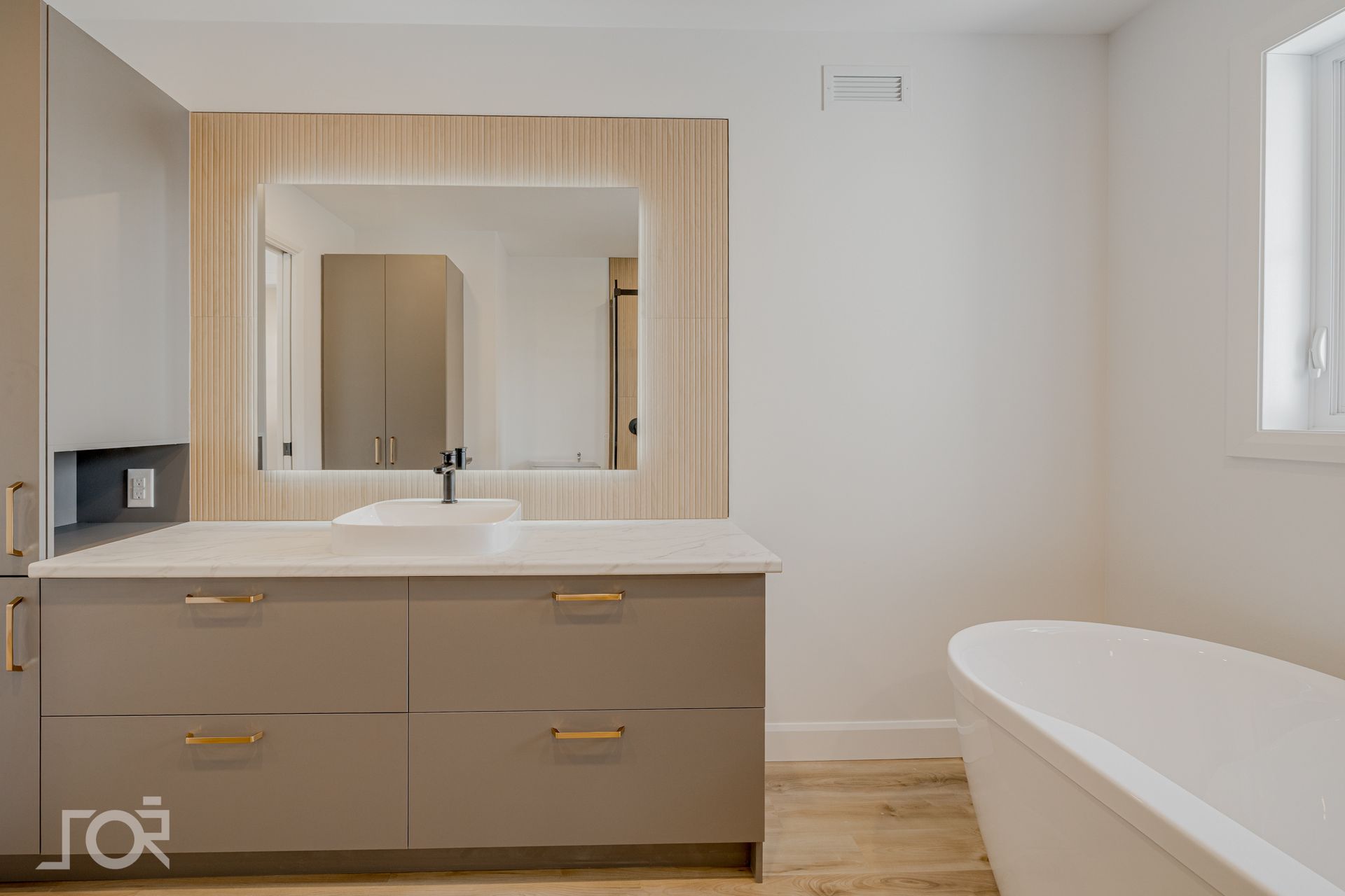 Salle de bains moderne avec un grand miroir, un meuble-lavabo gris et une baignoire blanche.