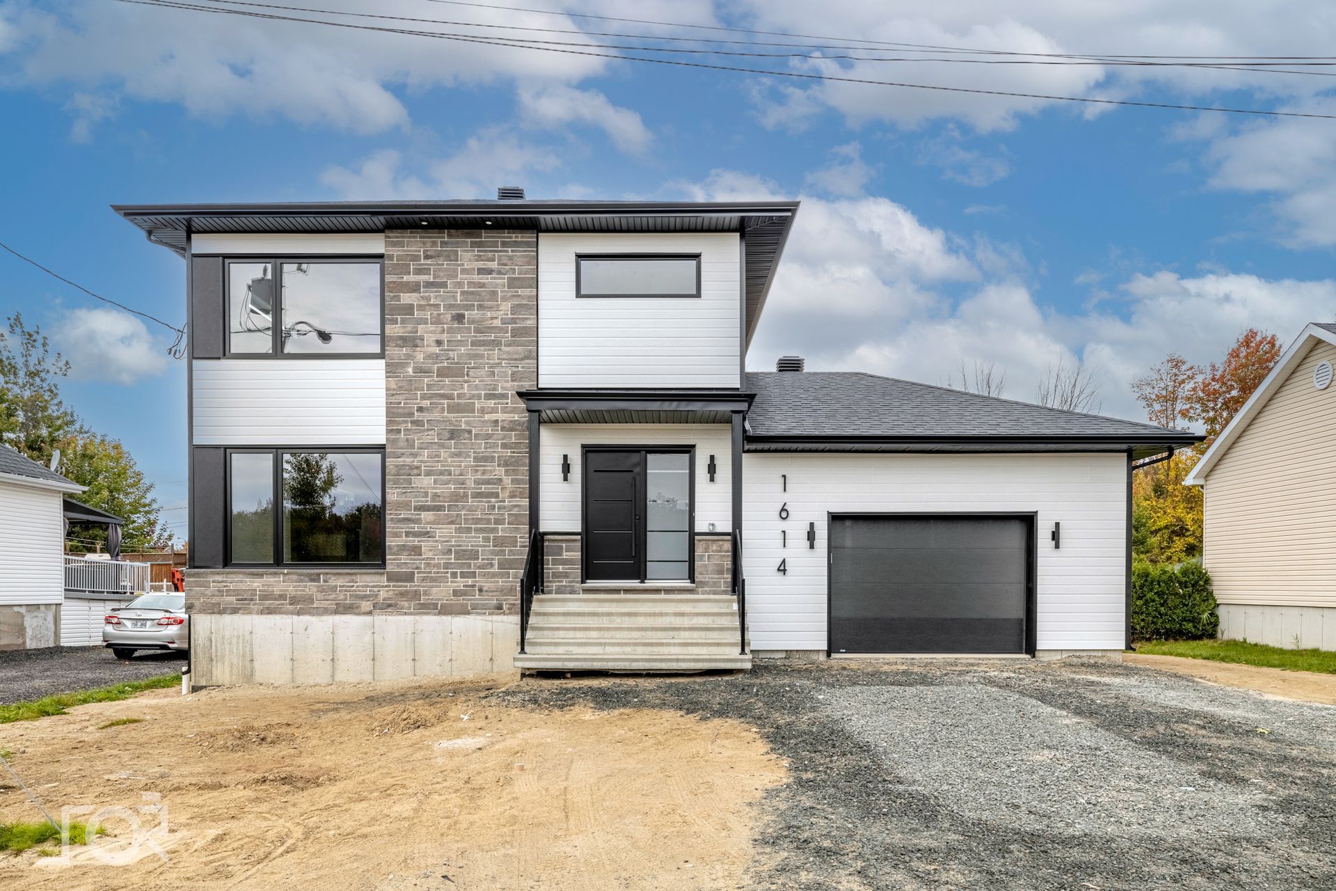 Une maison blanche avec une porte de garage noire est à vendre