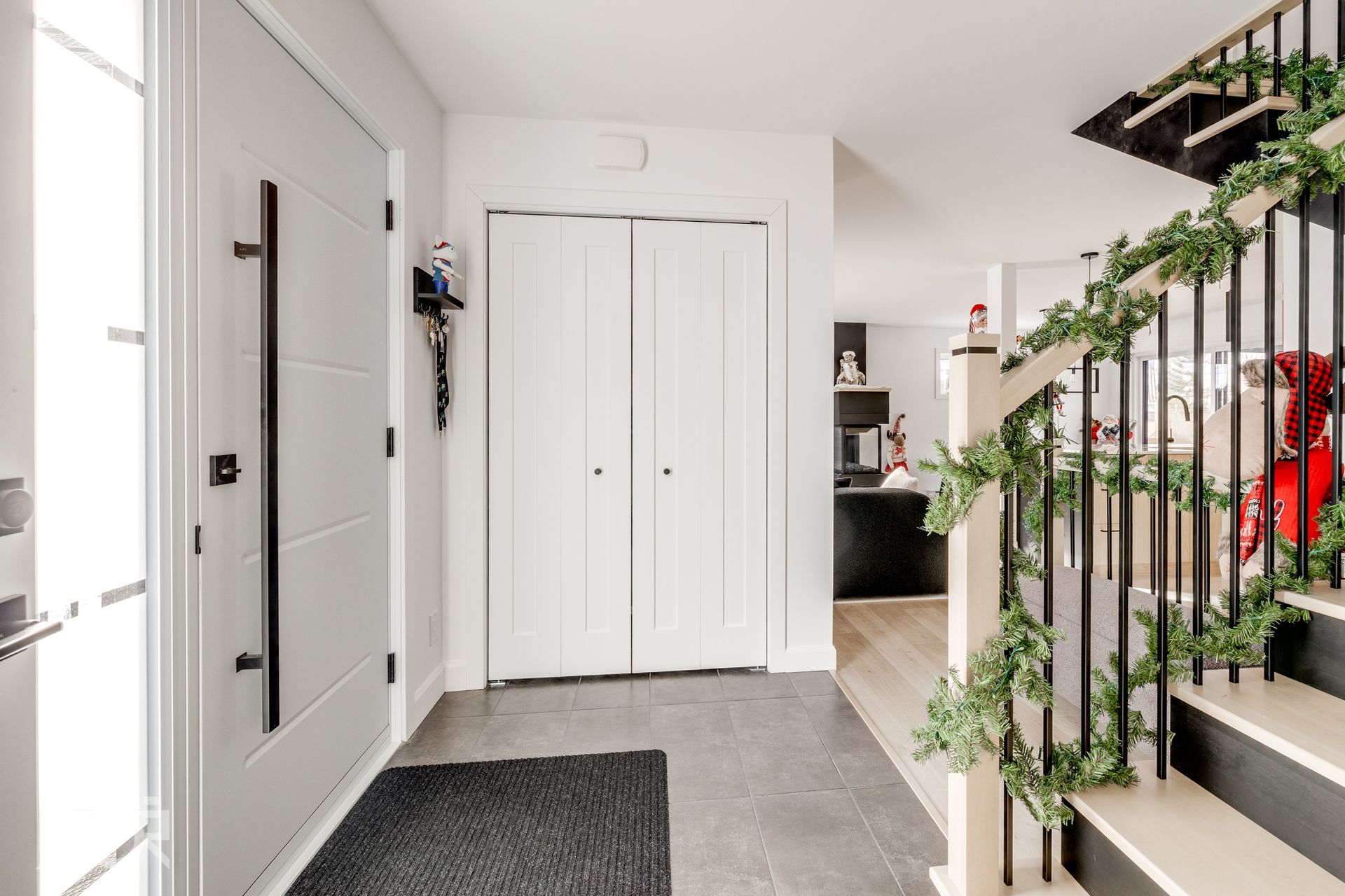 Un couloir avec des escaliers et une porte dans une maison décorée pour Noël.