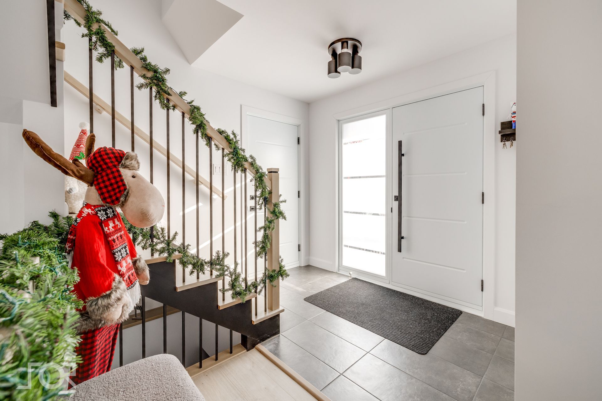 Un couloir avec un escalier et une porte décorée pour Noël.
