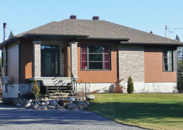 Une petite maison avec une allée de gravier devant elle