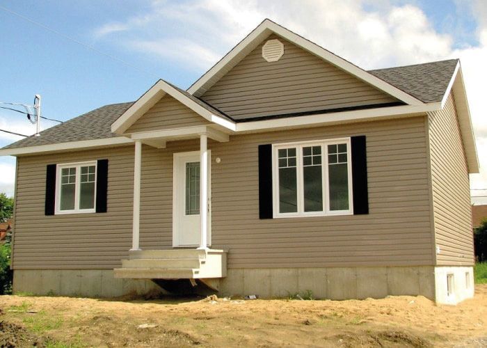 Une petite maison avec un porche et des volets noirs