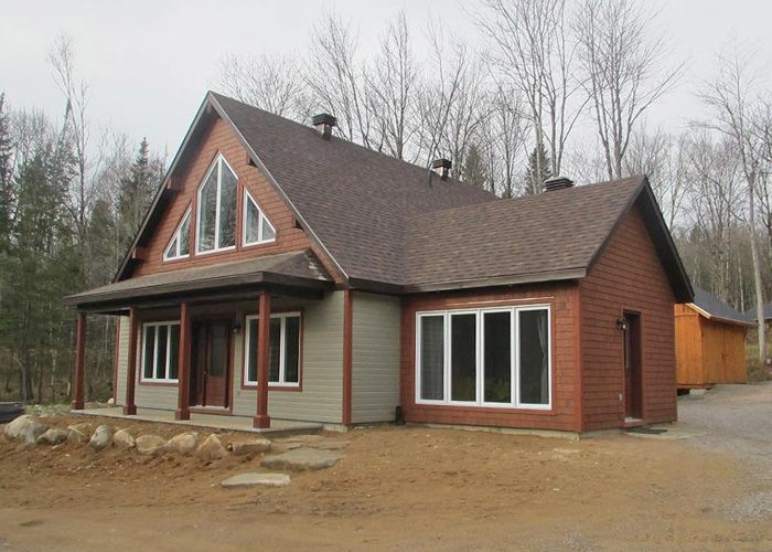 Une maison en brique avec un toit marron et beaucoup de fenêtres