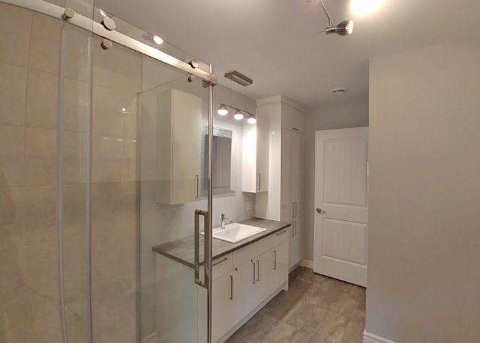Une salle de bain avec un lavabo et une douche avec portes coulissantes en verre.