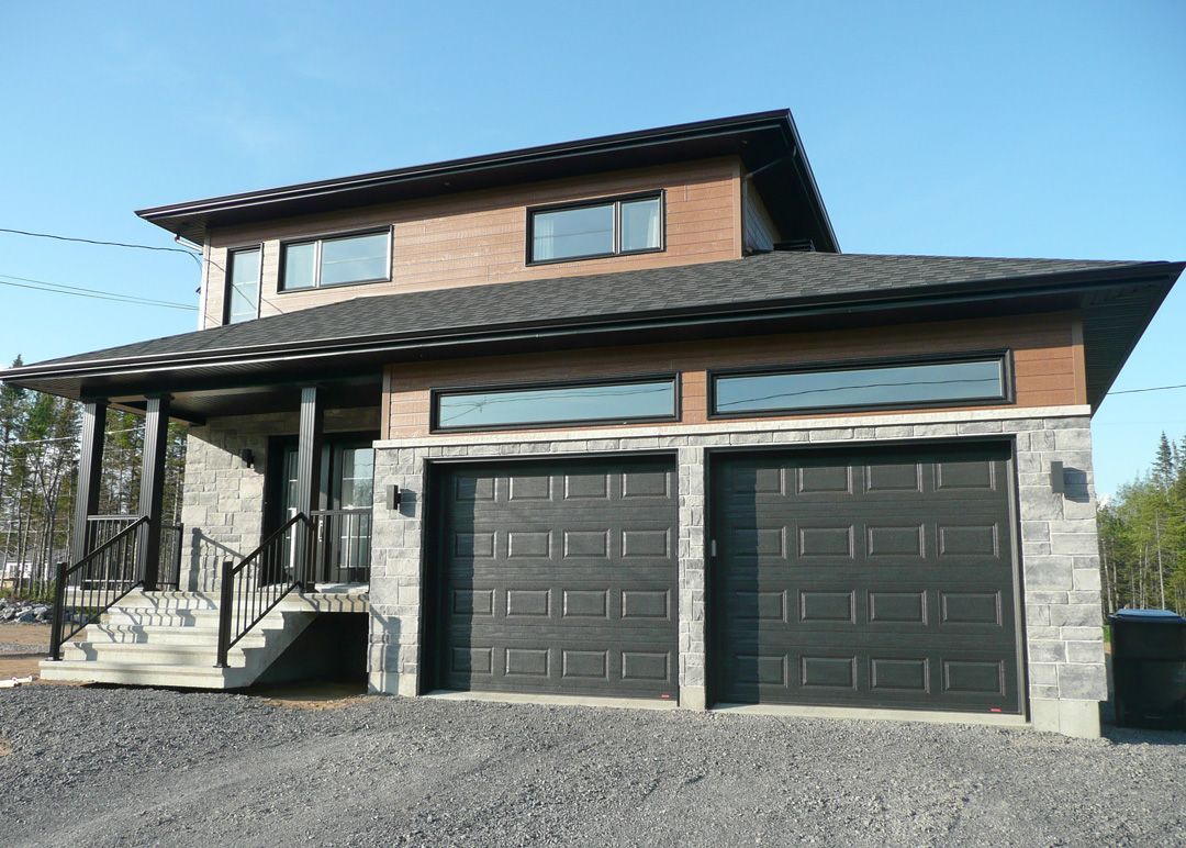 Une grande maison avec deux portes de garage et des escaliers