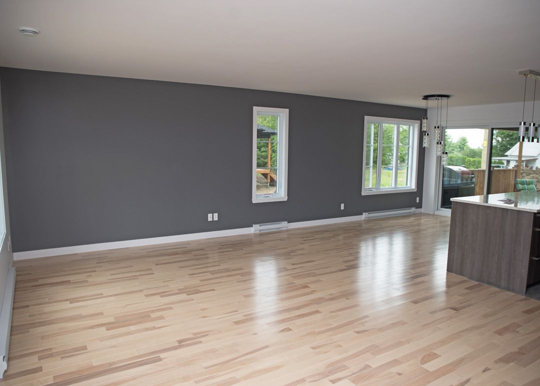 Un salon vide avec du parquet et des murs gris